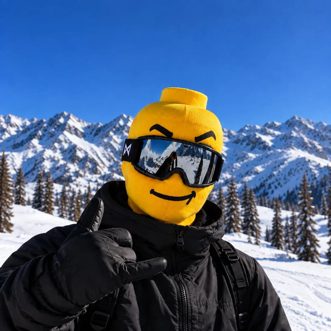 Person wearing a yellow knitted ski mask with a smiley face and ski goggles in the snow
